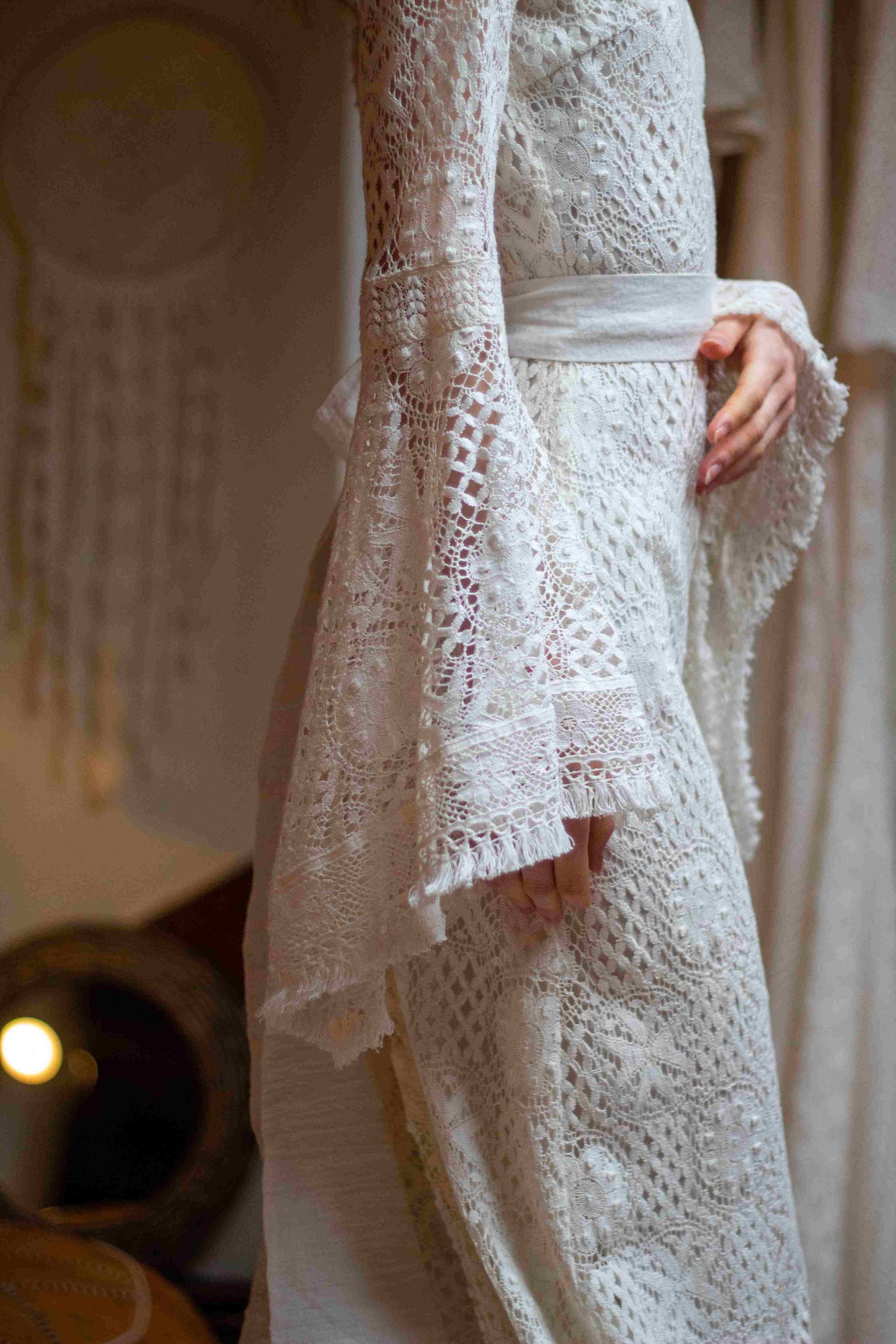 Bride wearing a modern lace wedding dress with a bell sleeve.
