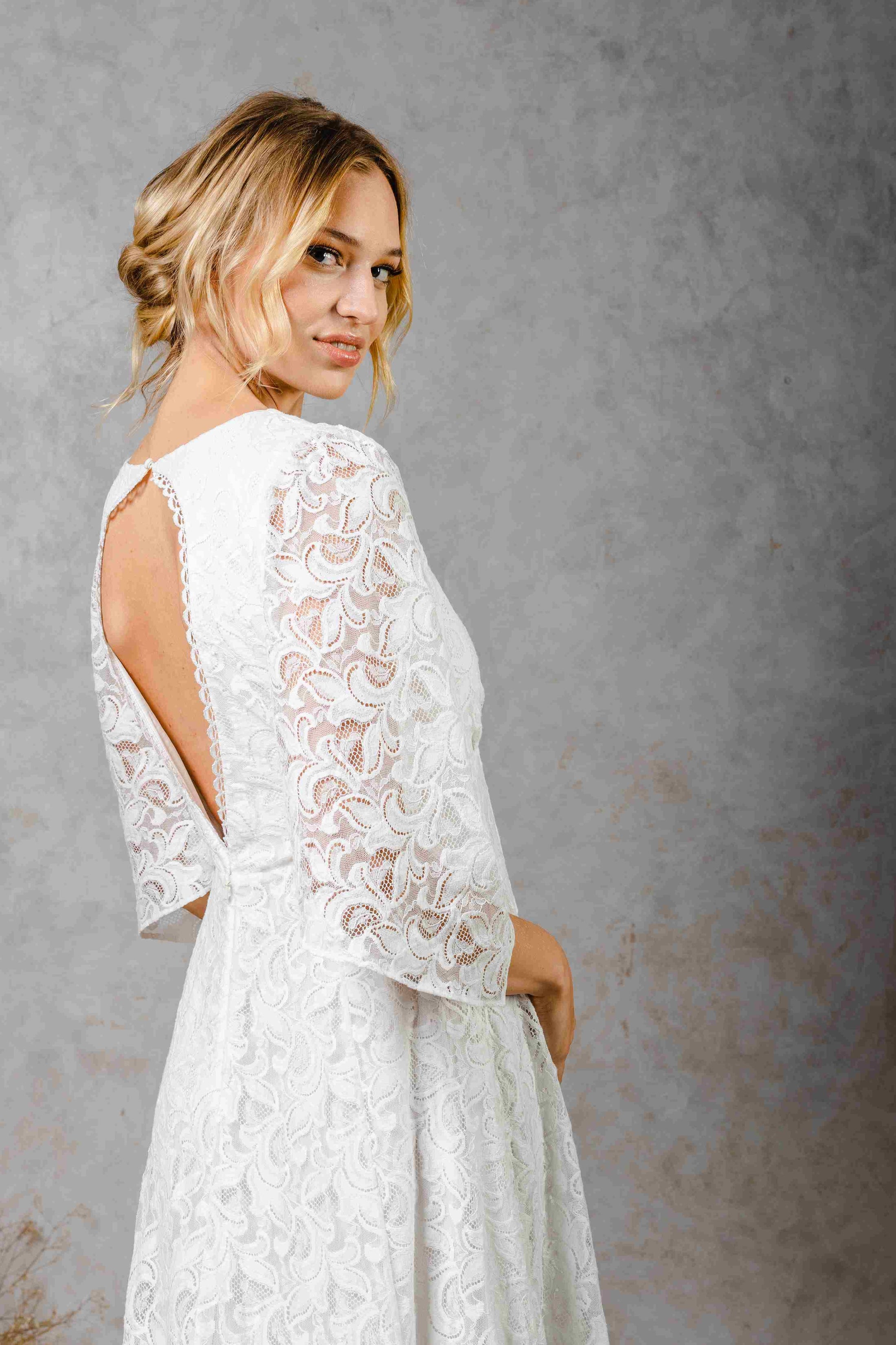 model wearing a modern bohemian lace wedding dress with bell sleeves