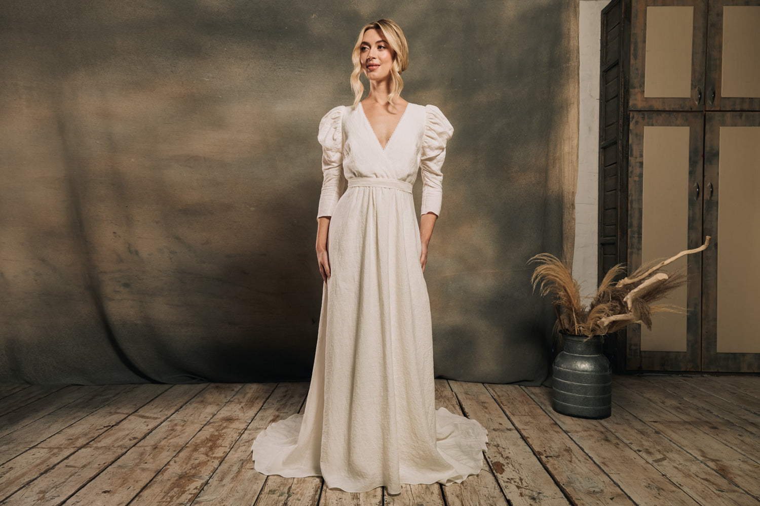 Model wearing modern bohemian wedding dress made from linen featuring leg of mutton sleeves and pockets.