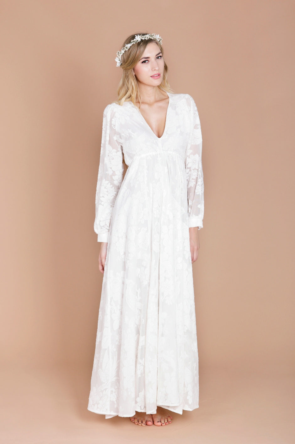A model wearing a modern bohemian wedding dress with sleeves.
