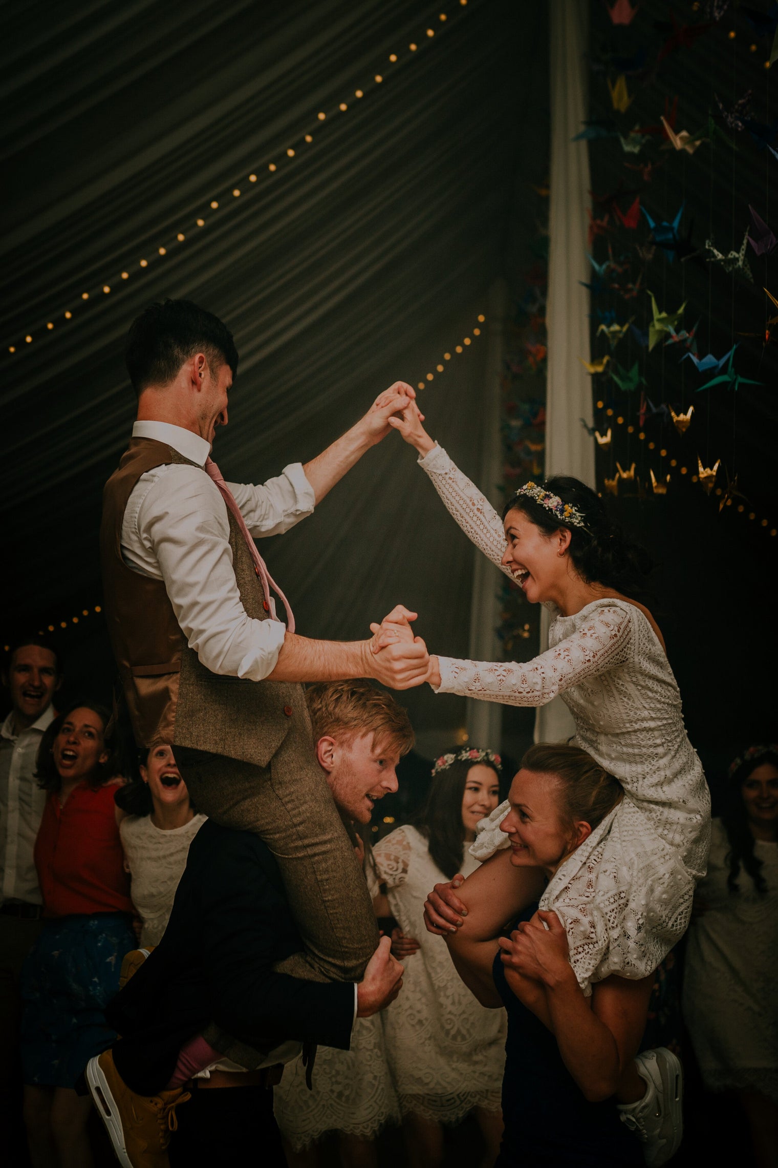Bride and groom on the shoulders of their friends.