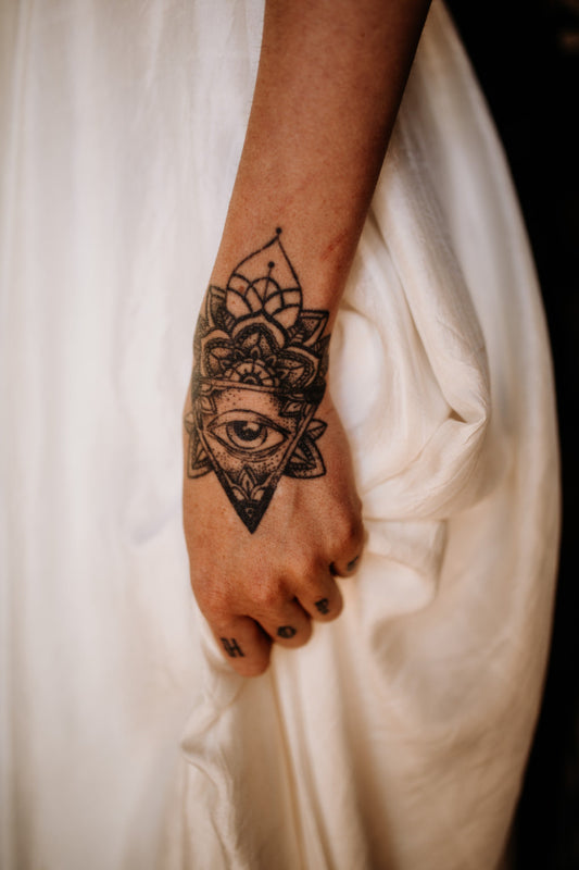 Tattooed bride holding her silk wedding dress