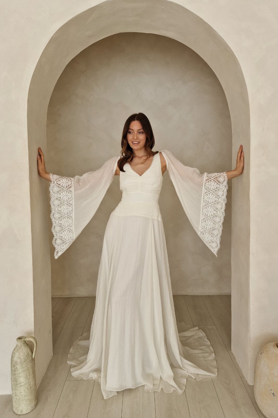 Model wearing a bohemian wedding dress with sleeves.