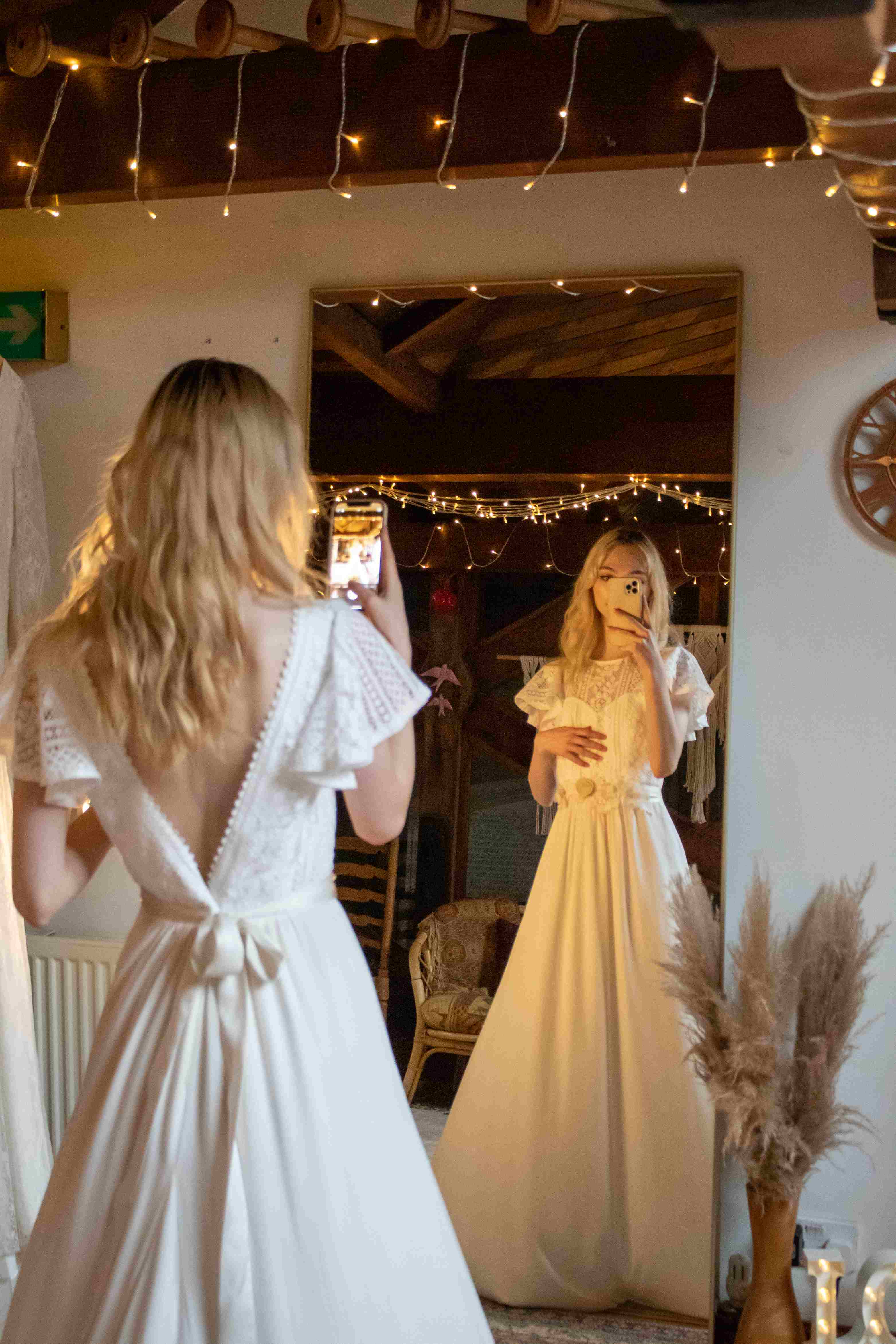 A bohemian bride taking a picture of herself in a bridal showroom.