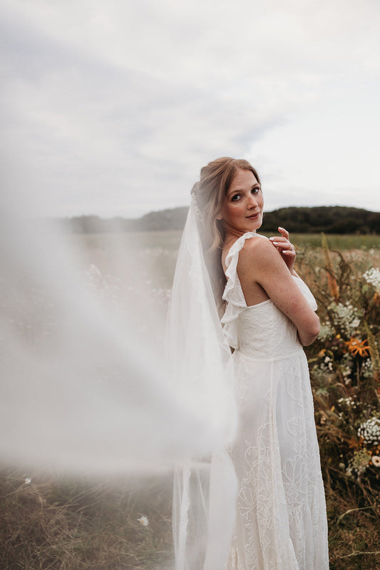 summer bride in a flower meadow wearing a modern bohemian wedding dress and a veil