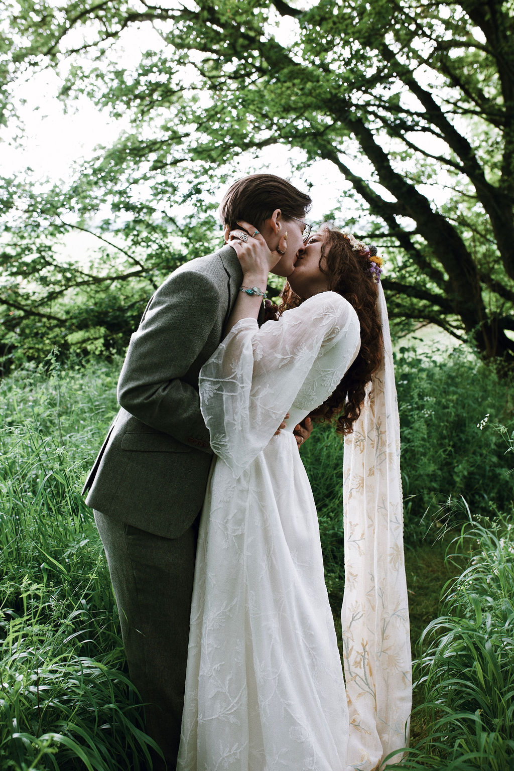 Boho bride and groom kissing in a forest.