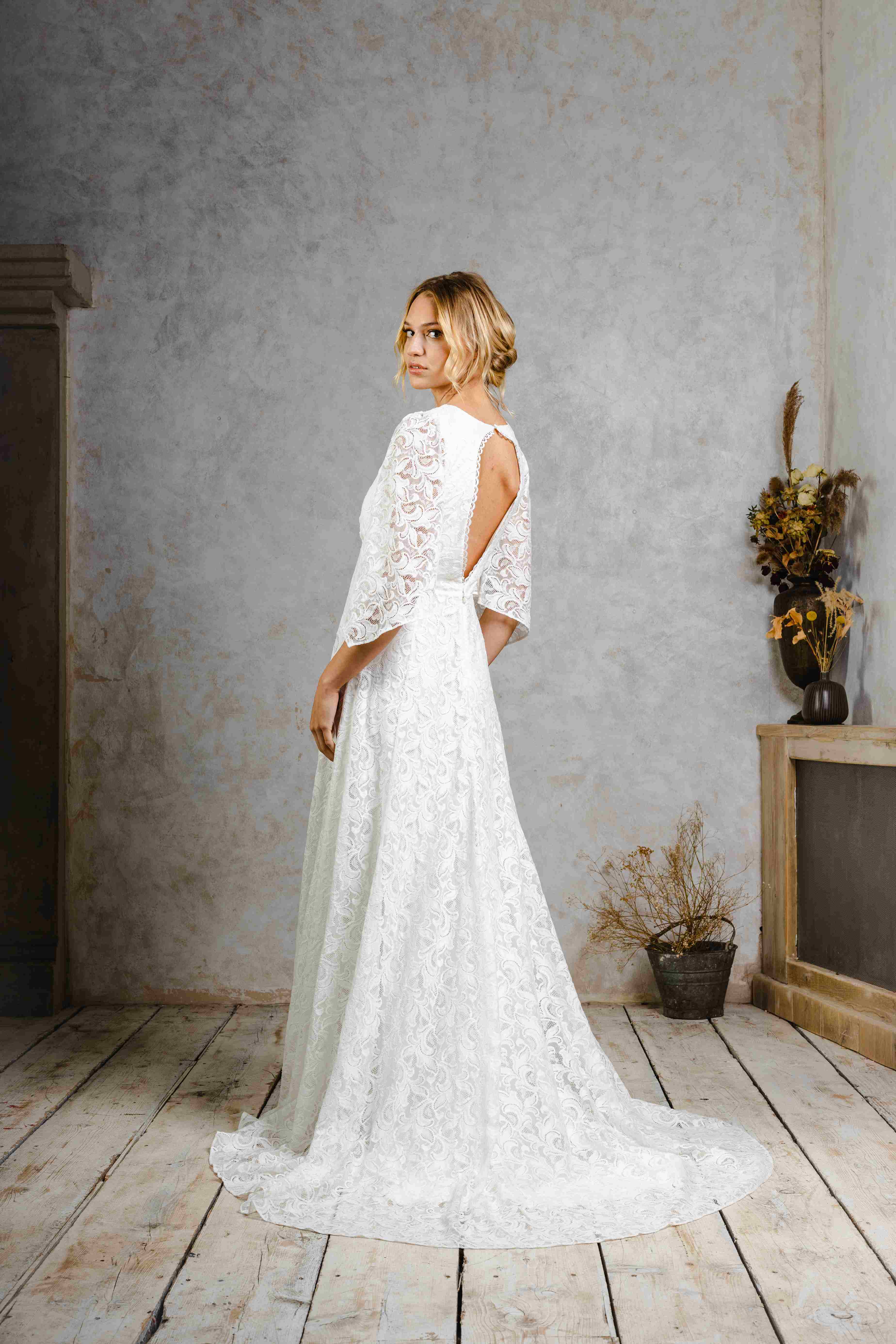 Model wearing a modern bohemian lace wedding dress with sleeves.