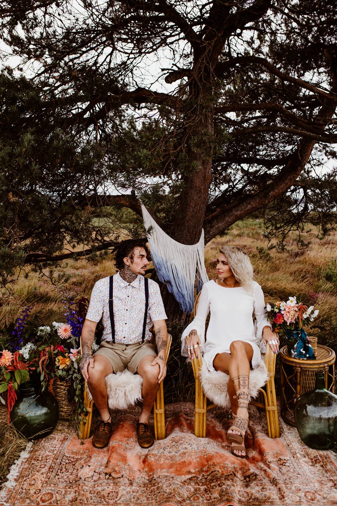 bride and groom sitting down under a tree at their nomad style wedding