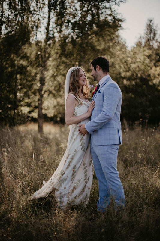 bride and groom holding each other in a meadow at their romantic flower garden inspired wedding at the Wellington Wood