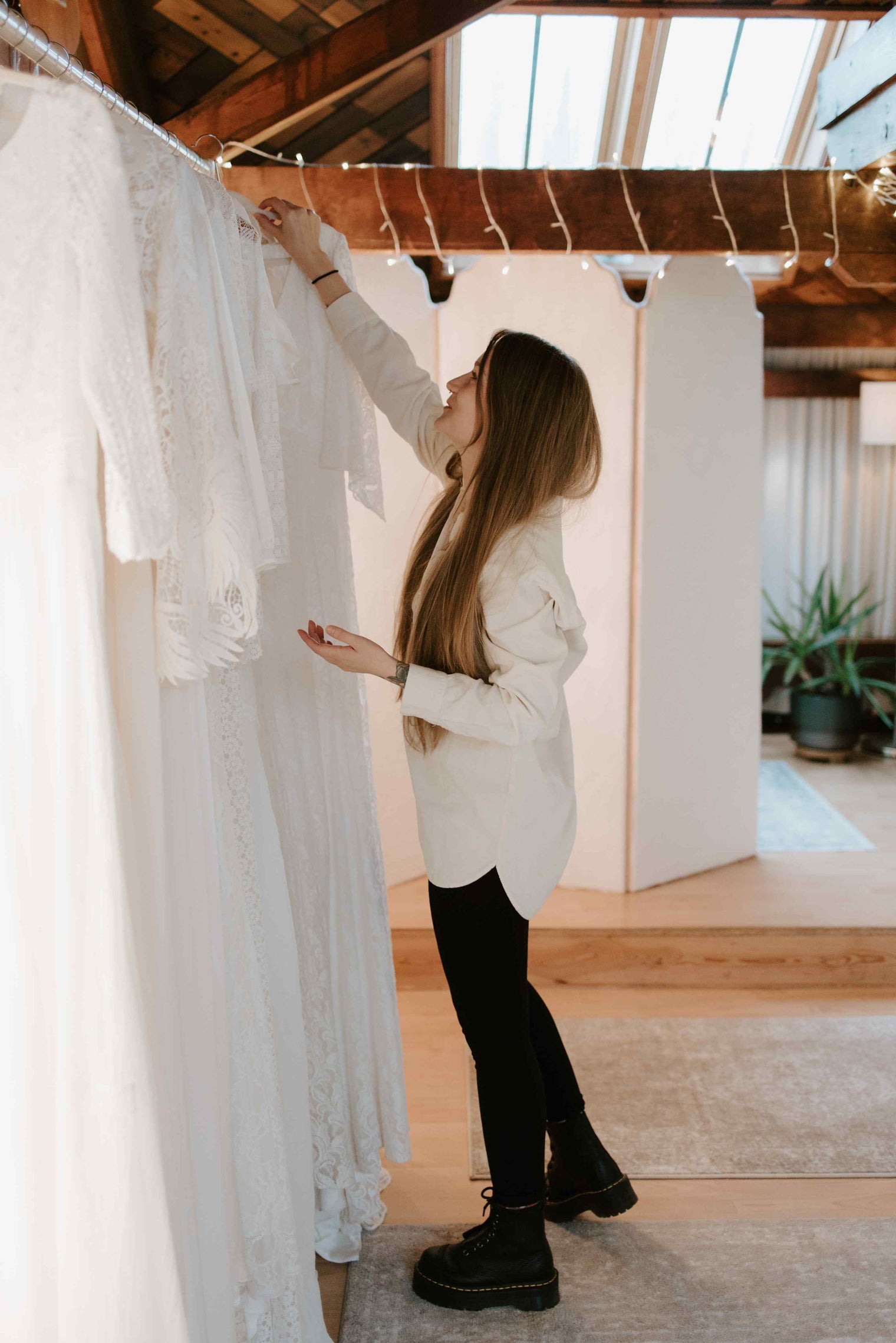 Woman reaching for a wedding dress in a bridal wear showroom.