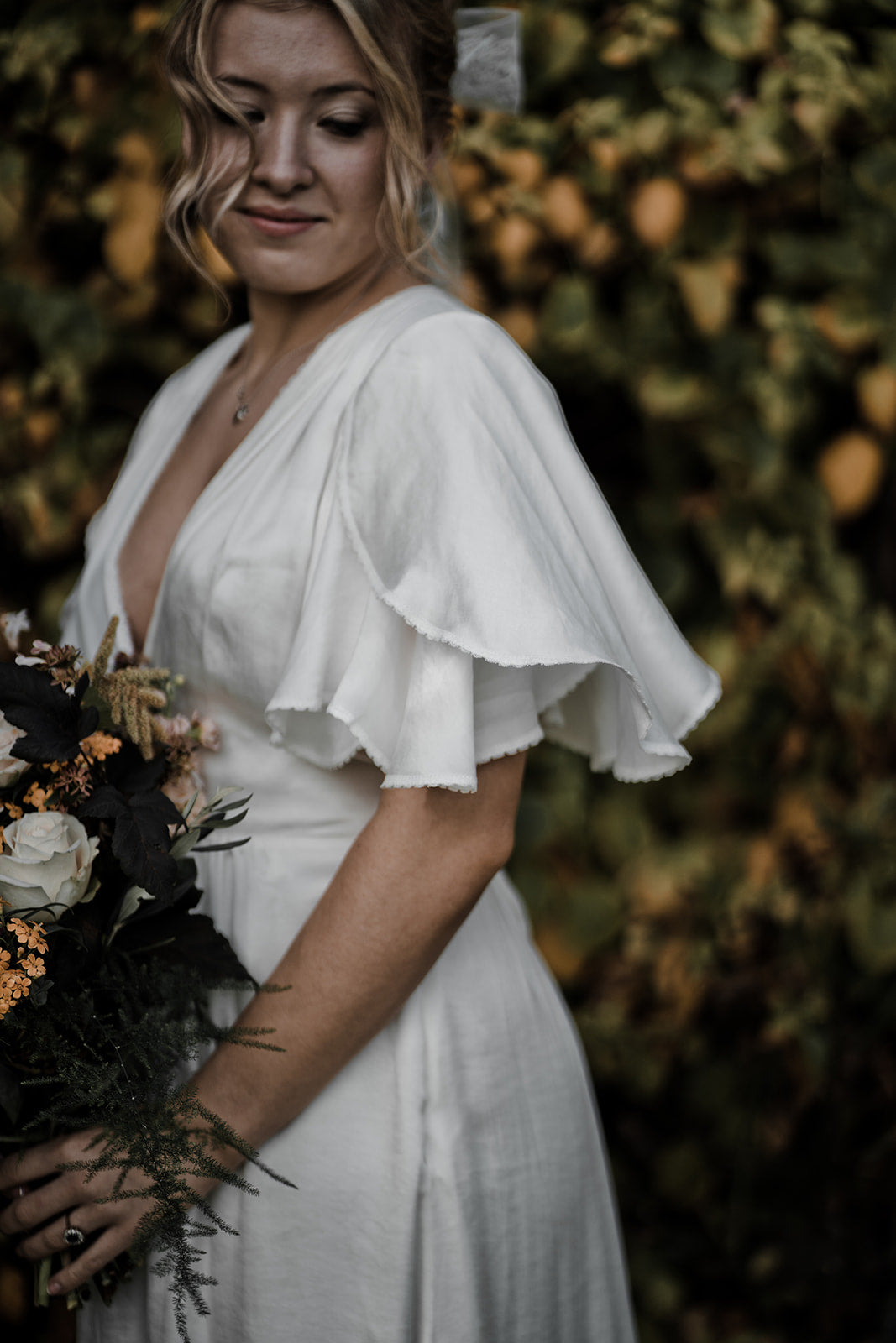 Model wearing a sustainable satin wedding dress with butterfly sleeves.