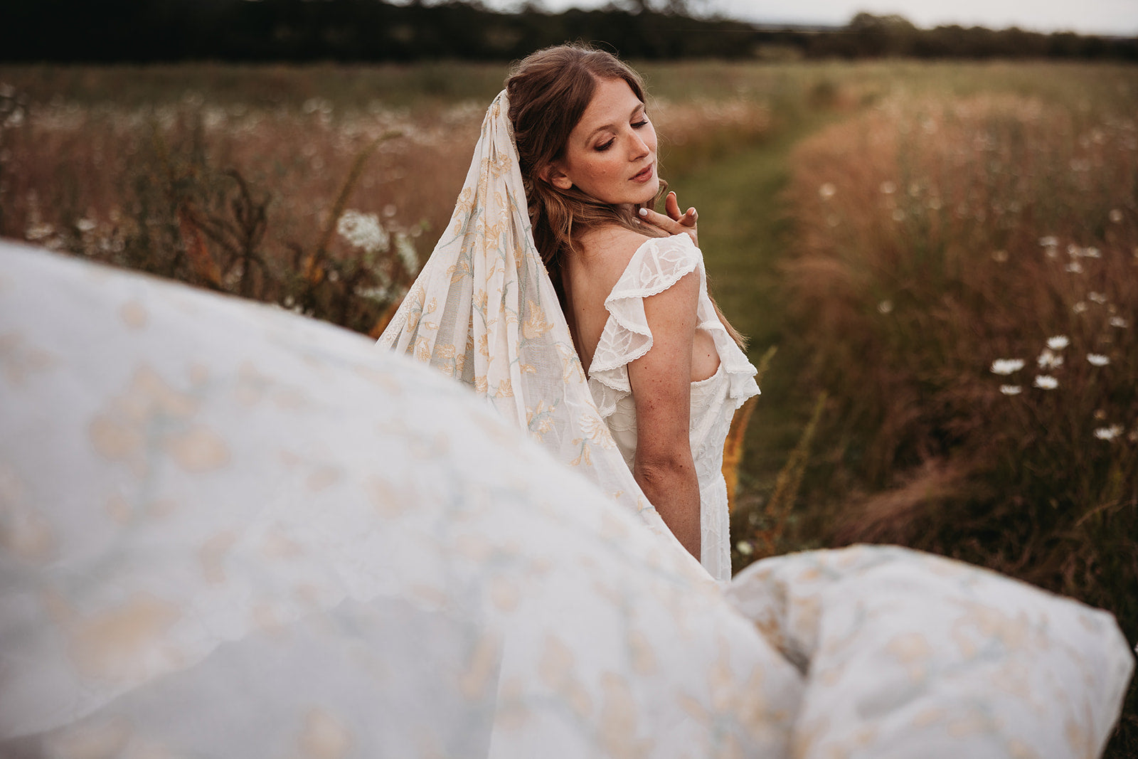 boho bride wearing a colourful bridal veil in a flower meadow