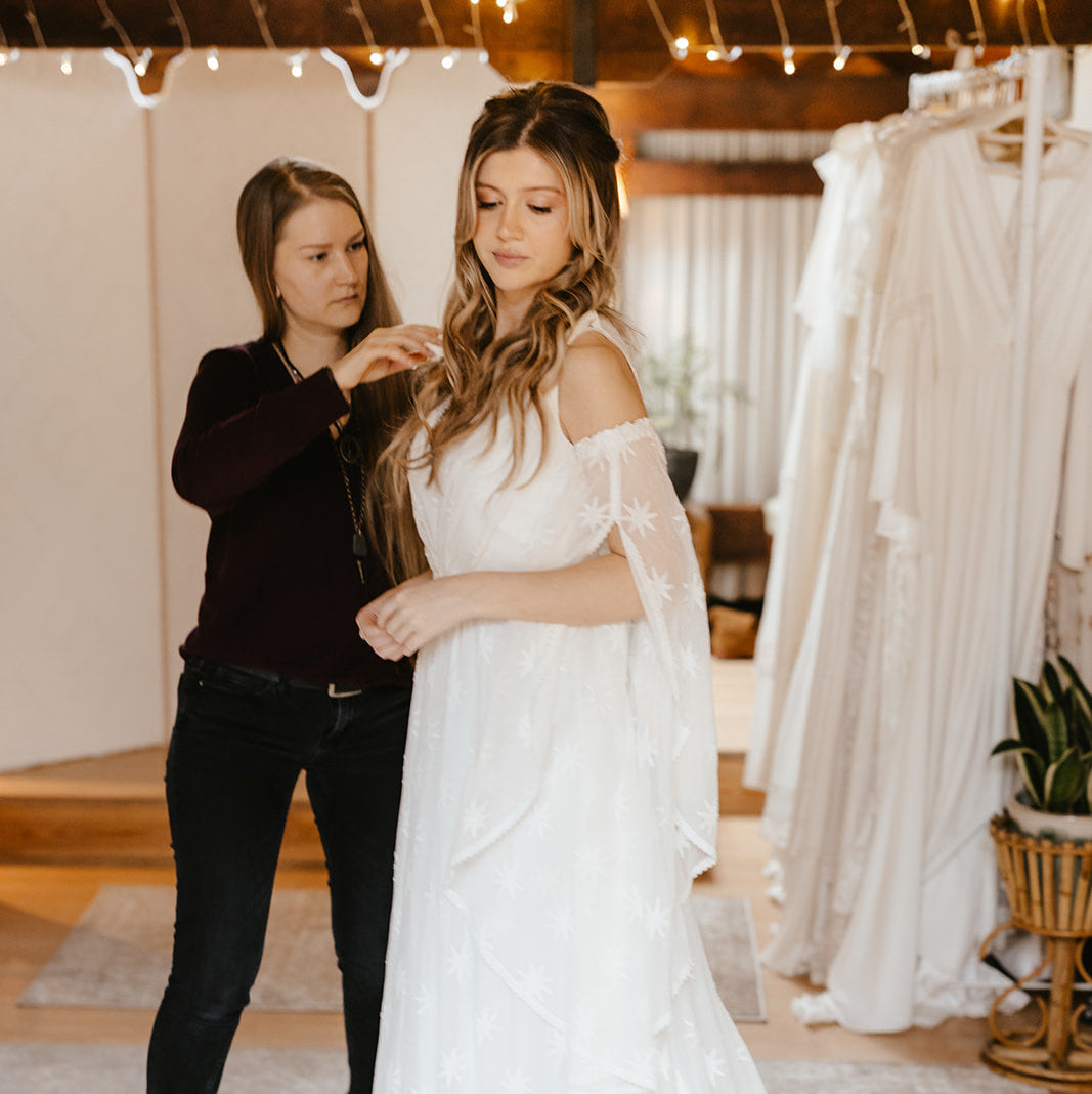 bridal consultant adjusting the wedding dress that a bride is wearing