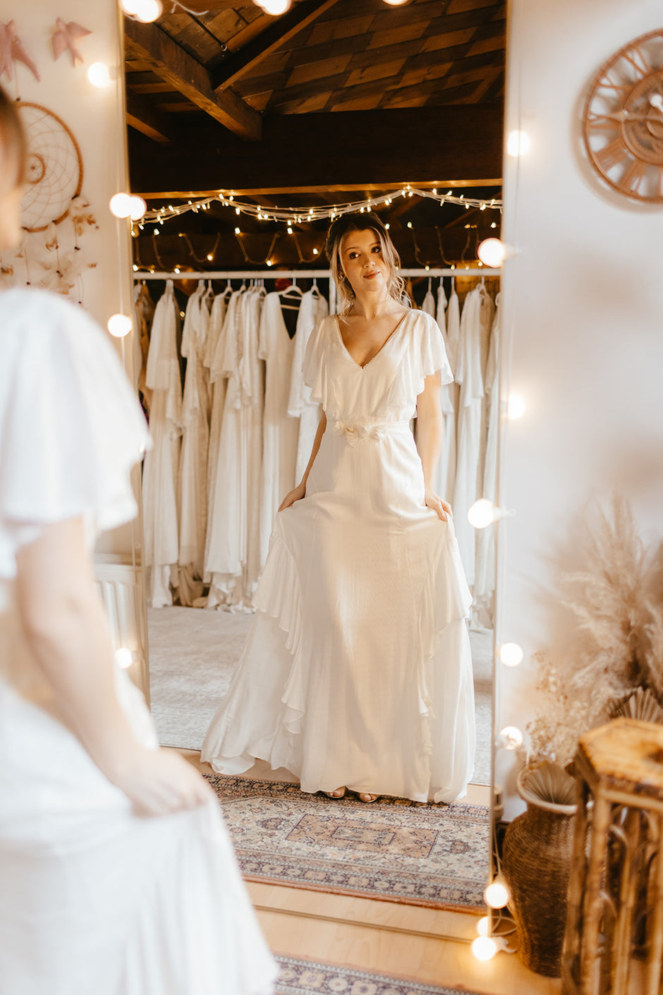 bride wearing a frilly wedding dress and looking at herself through a mirror