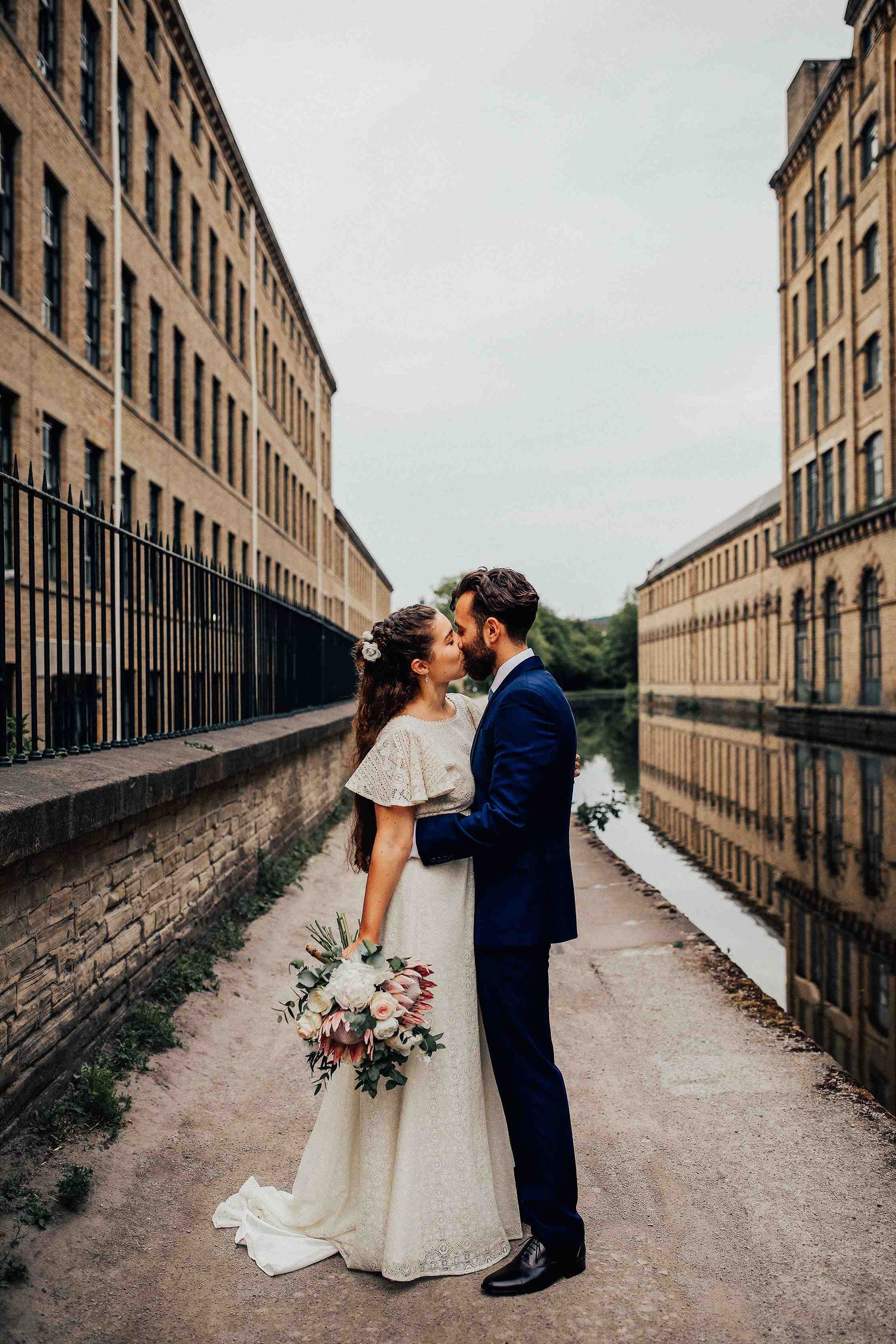 bride and groom kissing next to a canal