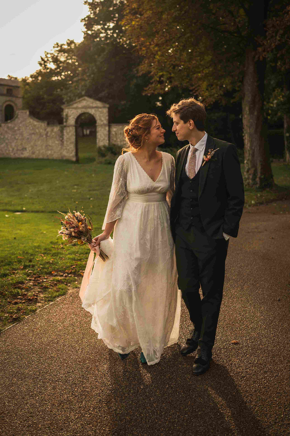 Bride and groom looking at each other on a pathway under a tree.