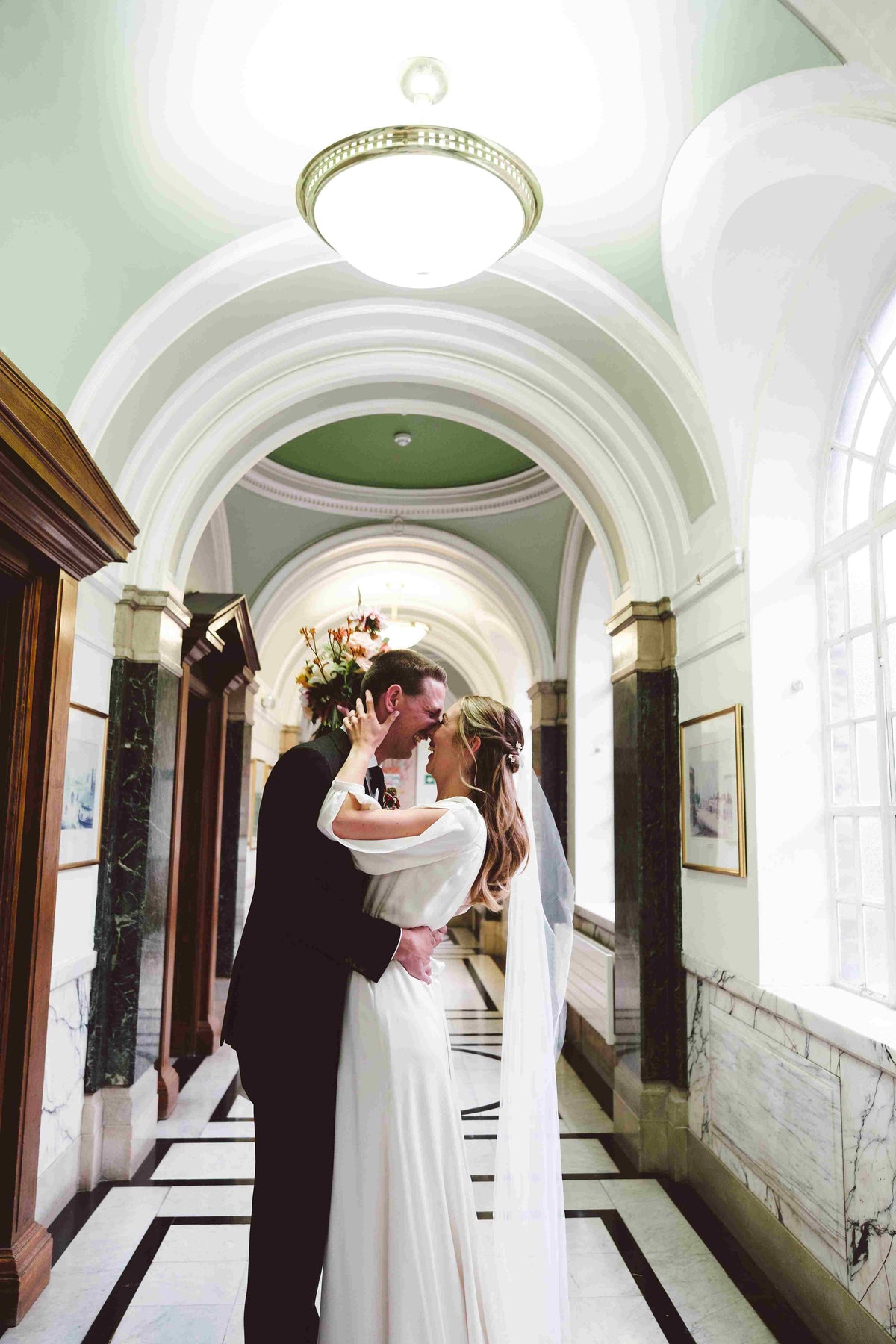 bride and groom kissing in a corridor