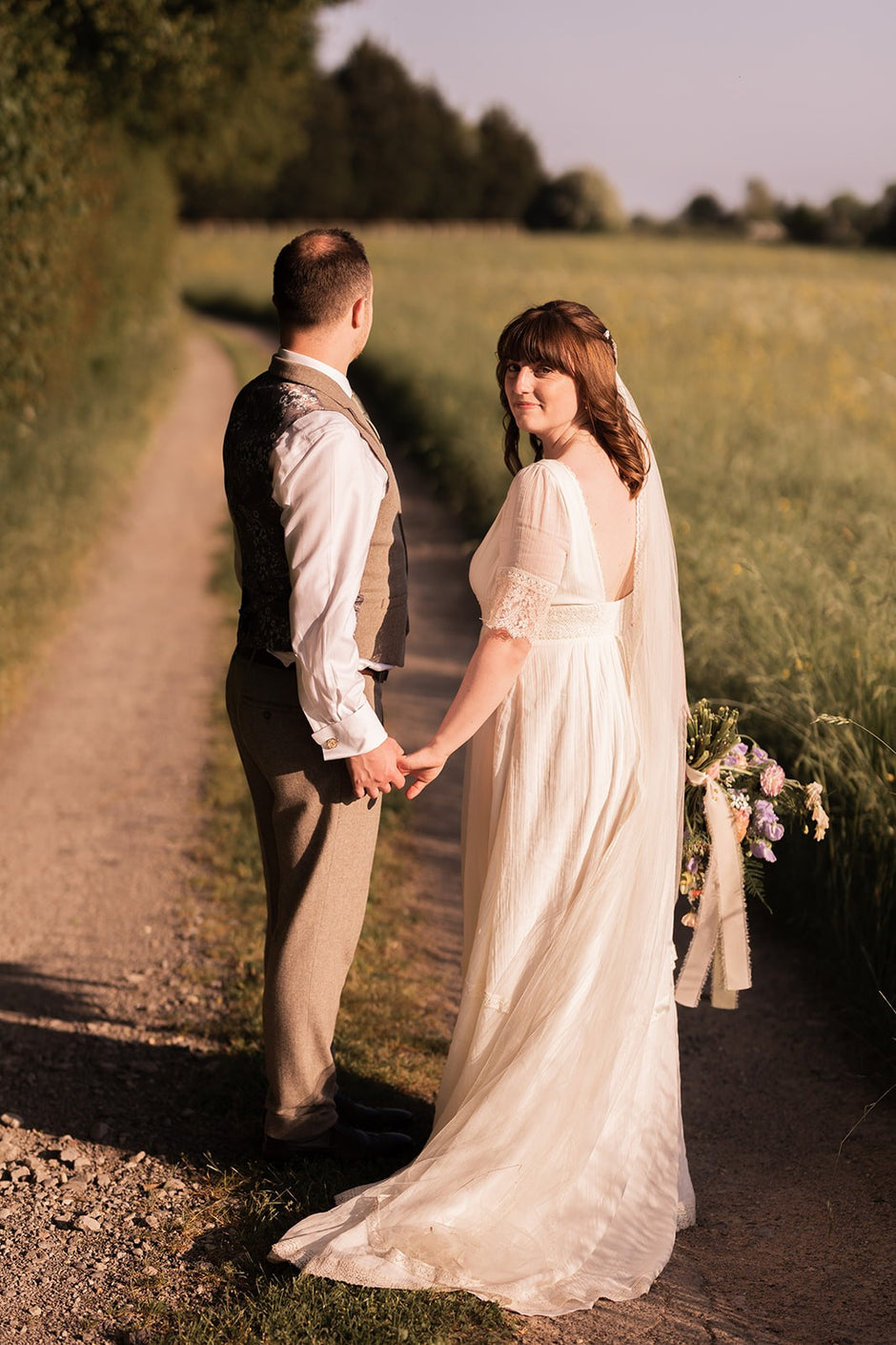 bride and groom holding hands on a country road