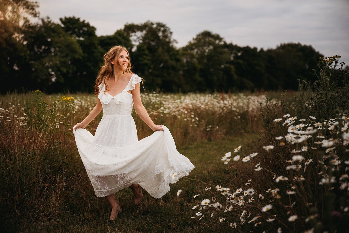 bride wearing a modern boho wedding dress walking in a flower meadow