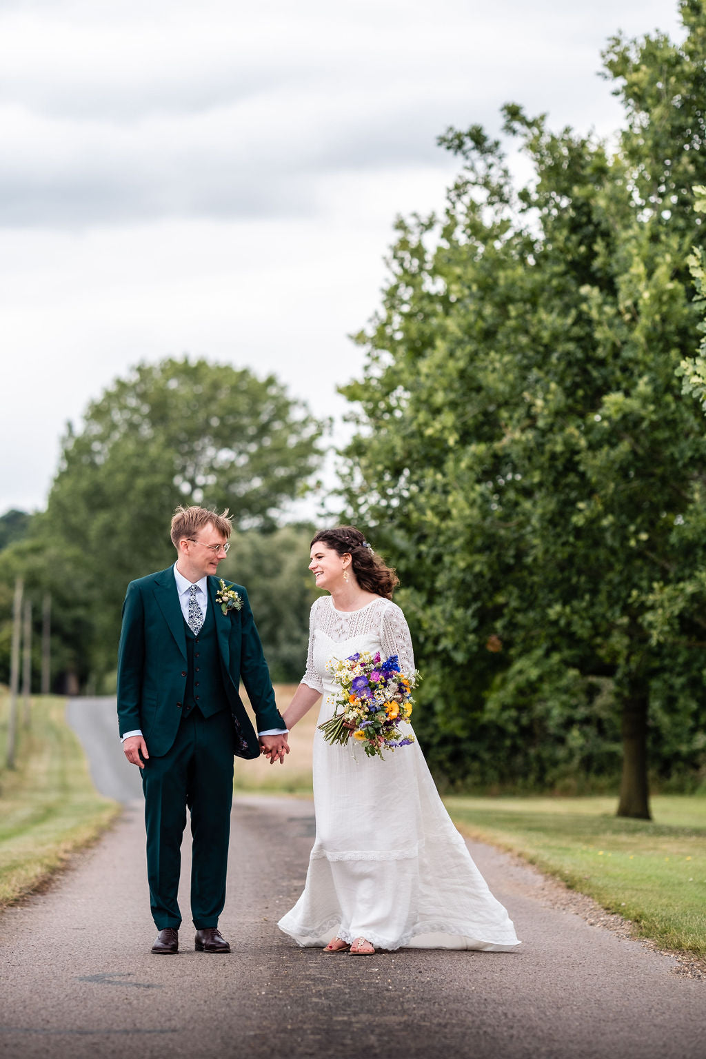 bride and groom holding hands on a country road