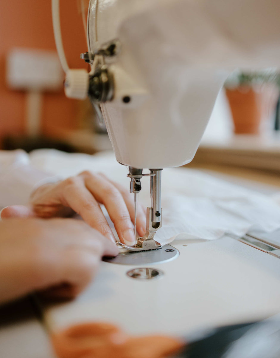 dressmaker sewing a wedding dress with an industrial sewing machine