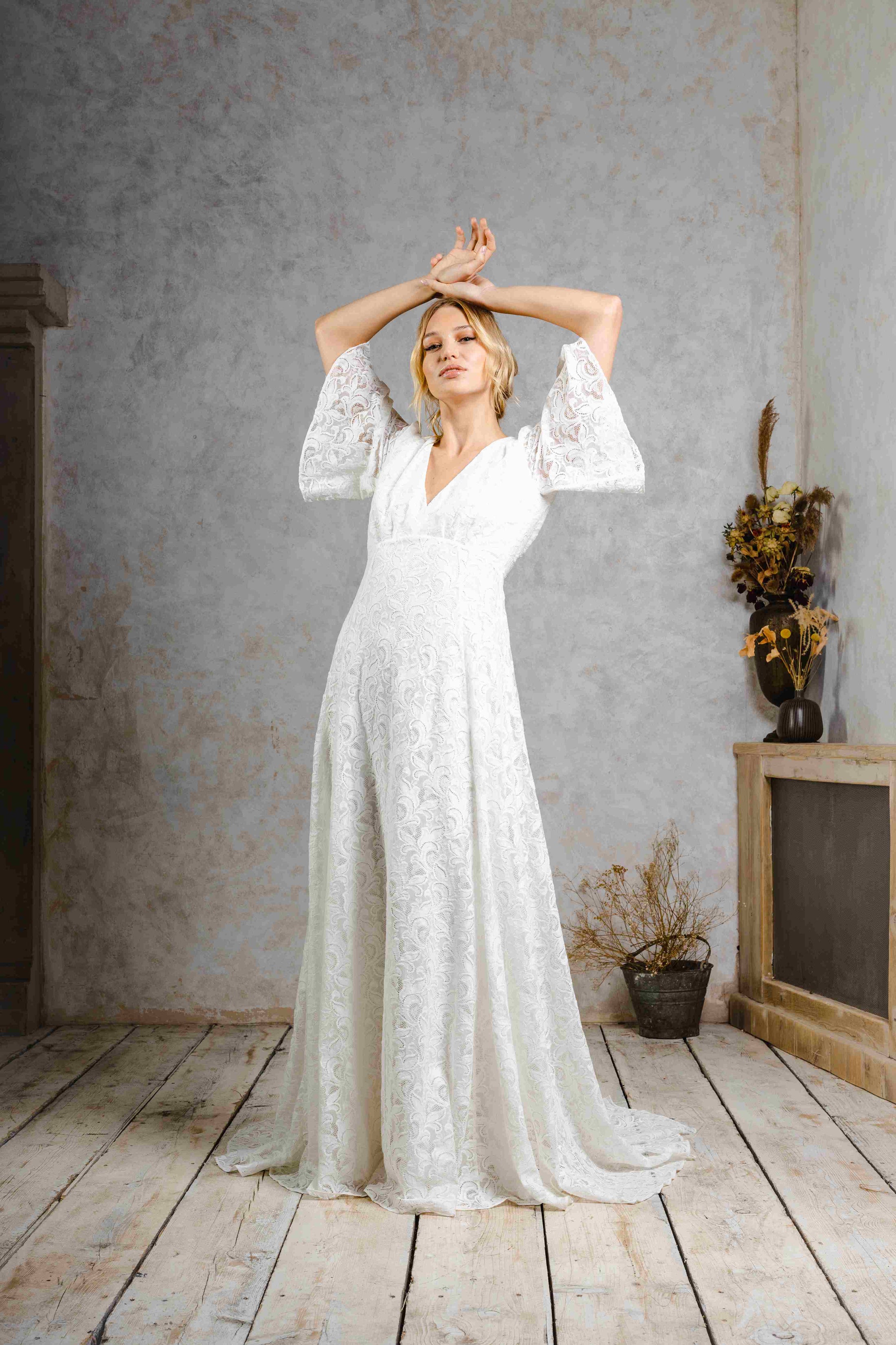 model wearing a modern bohemian lace wedding dress with bell sleeves