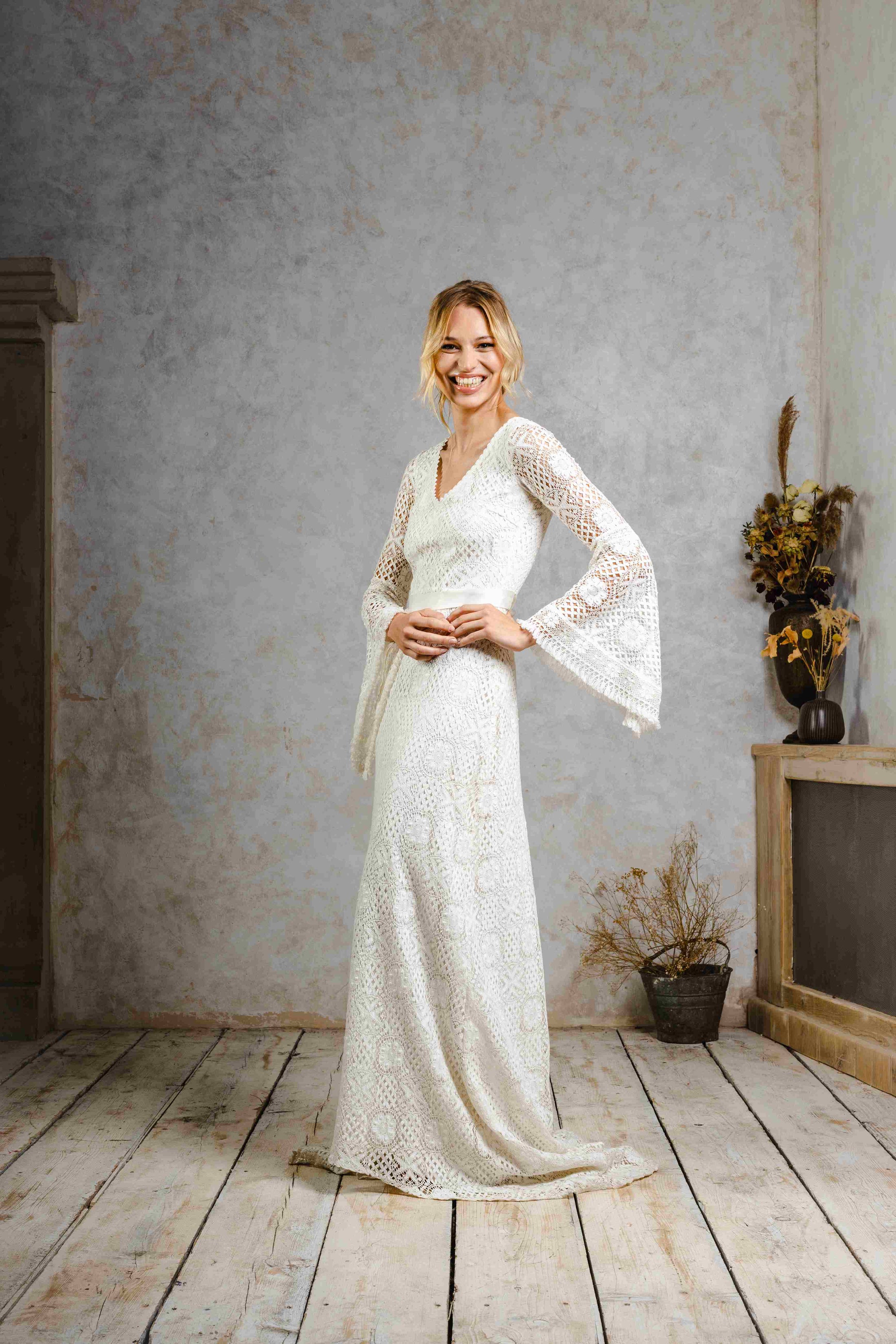 model wearing a modern bohemian lace wedding dress with bell sleeves