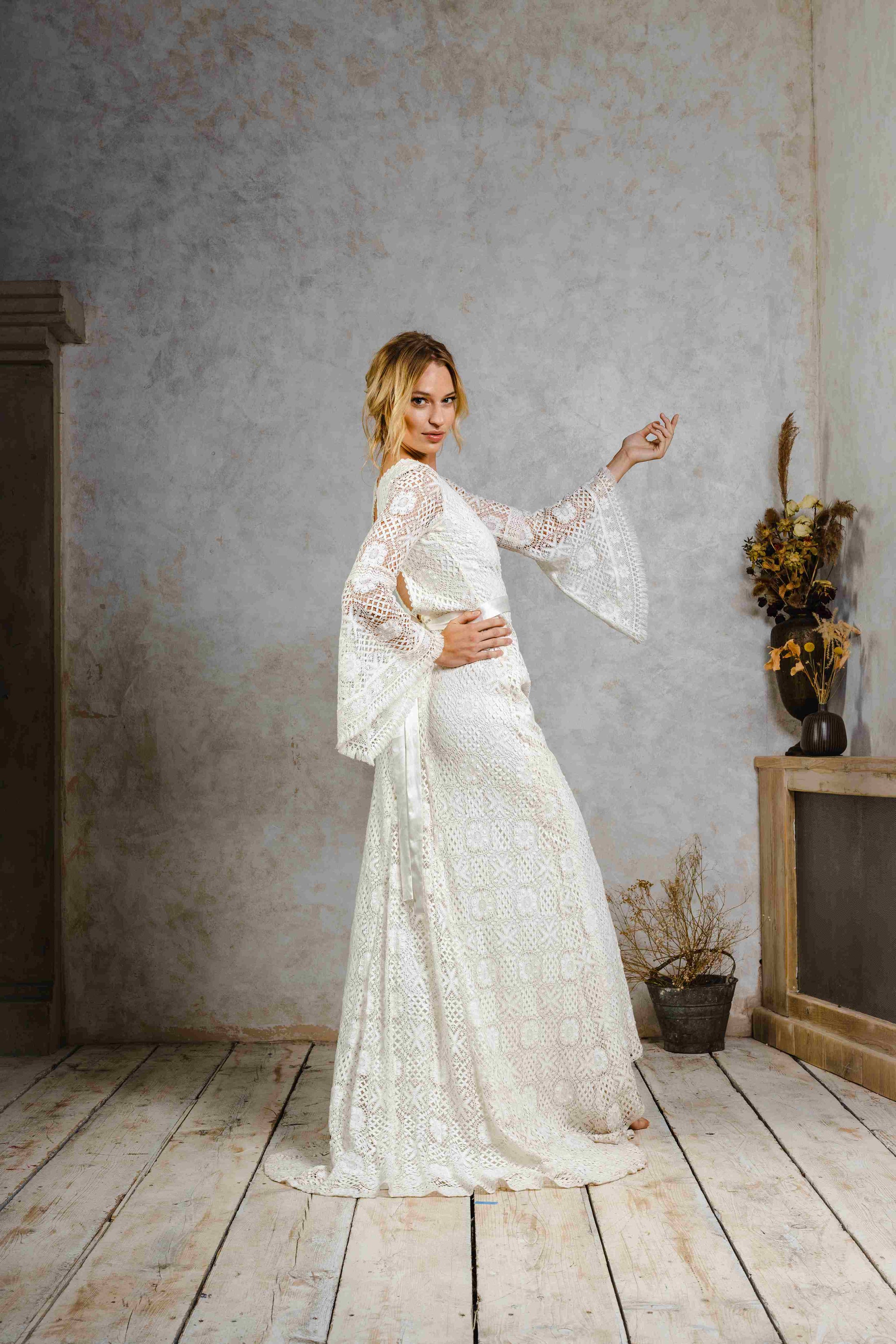 model wearing a modern bohemian lace wedding dress with bell sleeves