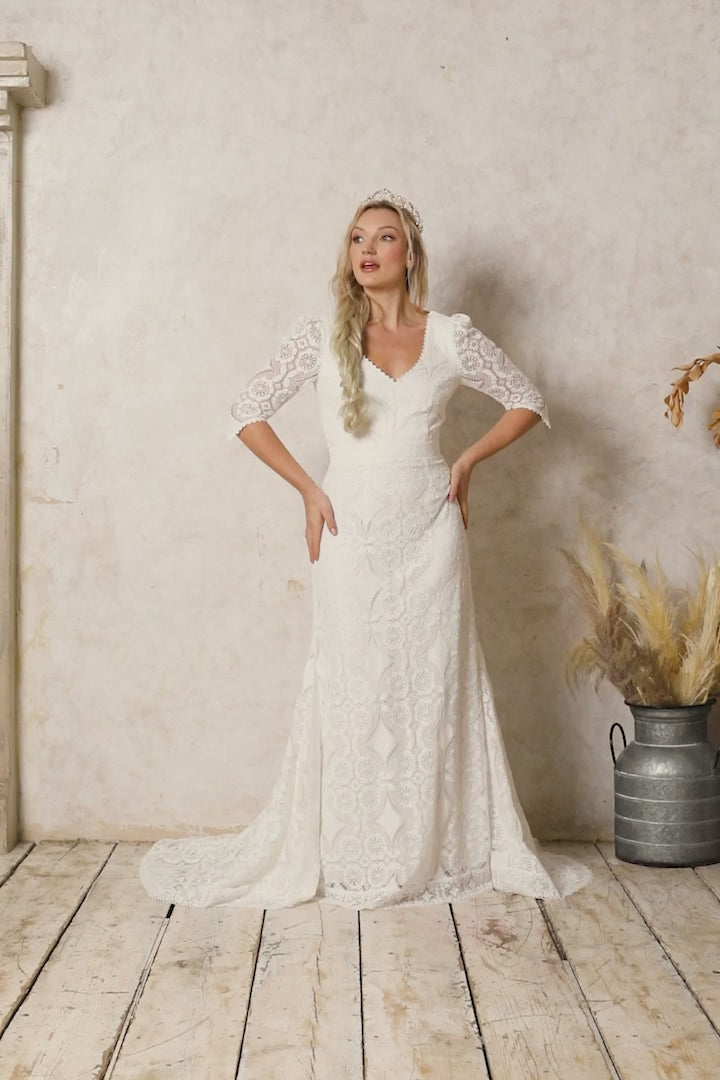 model wearing a fitted lace wedding dress with pointy sleeves