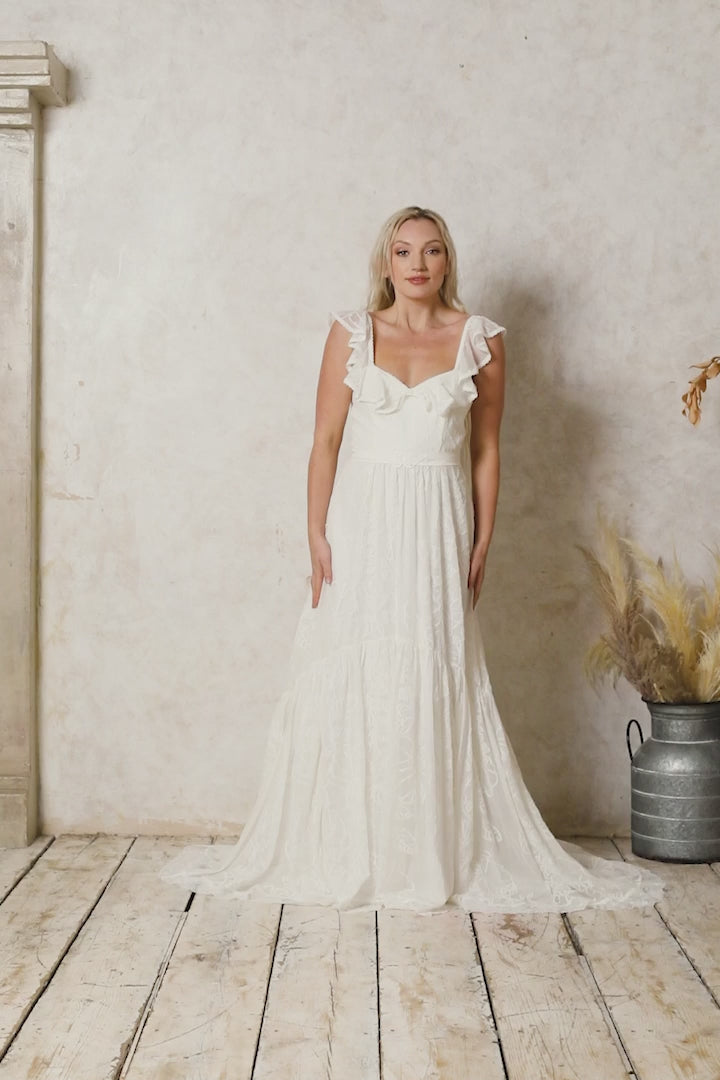 model wearing a modern bohemian lace wedding dress with frilly straps