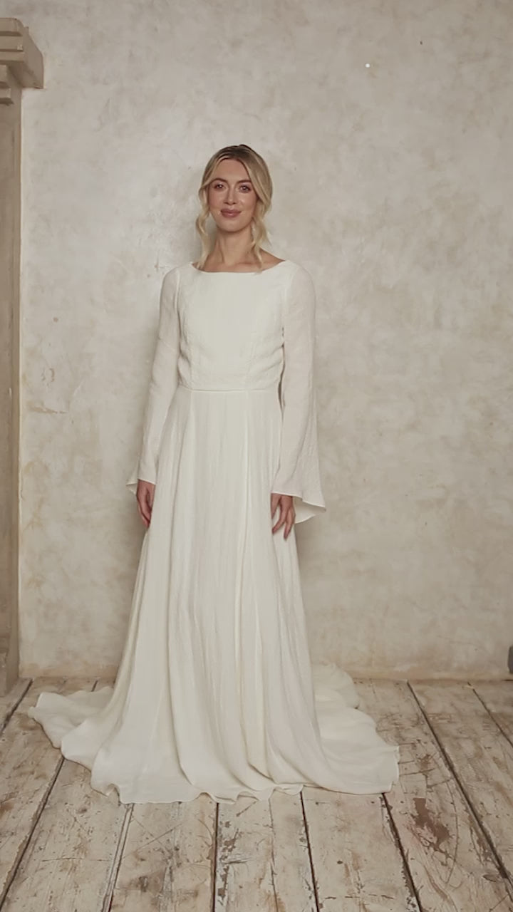 model wearing a linen wedding dress with a boat neckline and bell sleeves