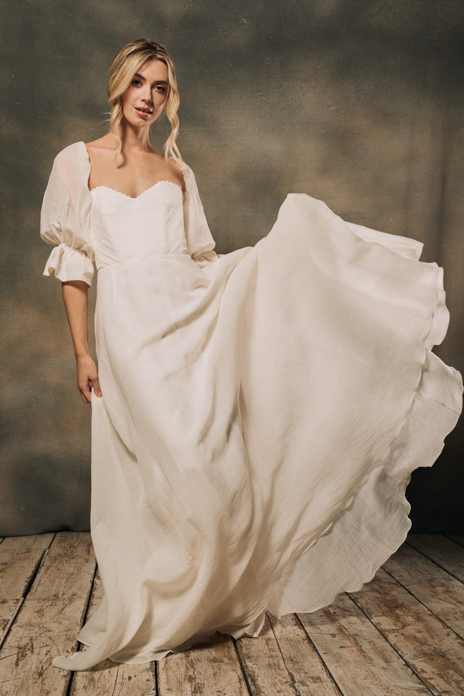 A model wearing a modern strapless wedding dress with detachable sleeves.