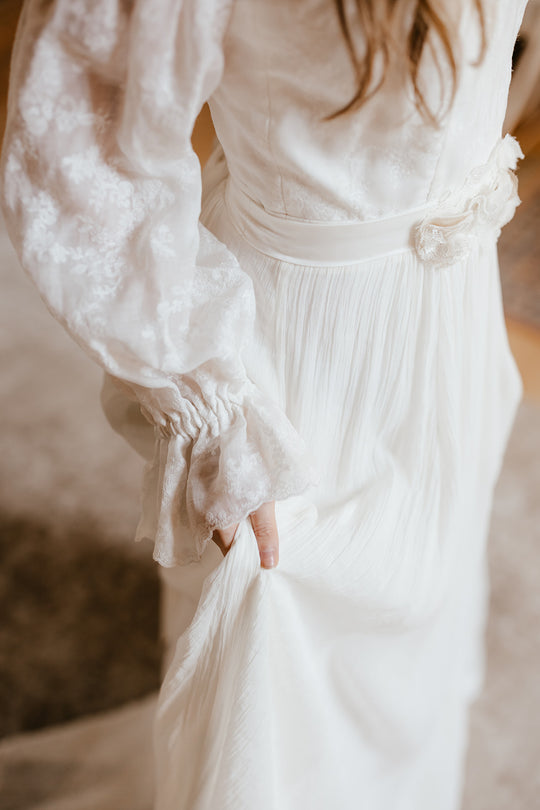 bride wearing a sustainable wedding dress with billowy sleeves and a flower sash